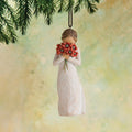 Willow Tree Surrounded by Love Ornament, 4”h hand-painted resin figure in cream dress holding bouquet of poppies to face, brown elastic cord, hanging in front of dark yellow painting