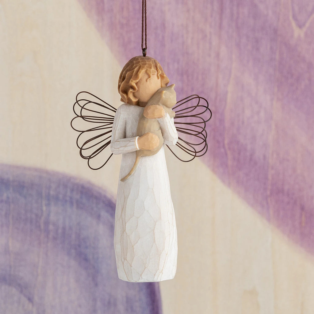 Willow Tree With affection Ornament, 4.5”h hand-painted resin figure in cream dress with wire wings, holding gray cat, brown elastic cord, hanging in front of purple painting