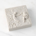Closed white resin box; lid carved with figural and organic imagery
