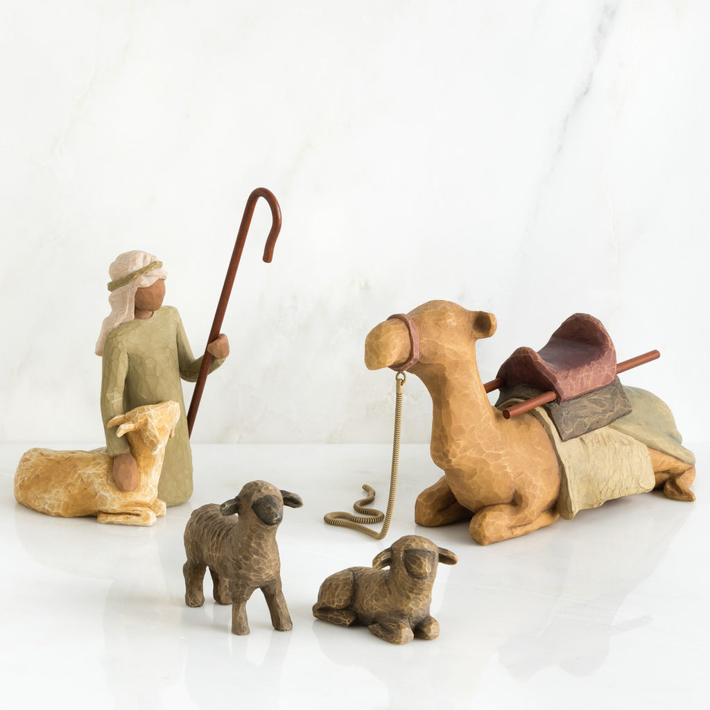 Set of figurines - golden camel laying down surrounded by two grey sheep and wiseman petting golden lamb