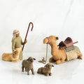 Set of figurines - golden camel laying down surrounded by two grey sheep and wiseman petting golden lamb