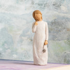 Willow Tree Remember, 5.5”h hand-painted standing resin figure in cream dress holding drooping wire flower in hand, in front of grey painting