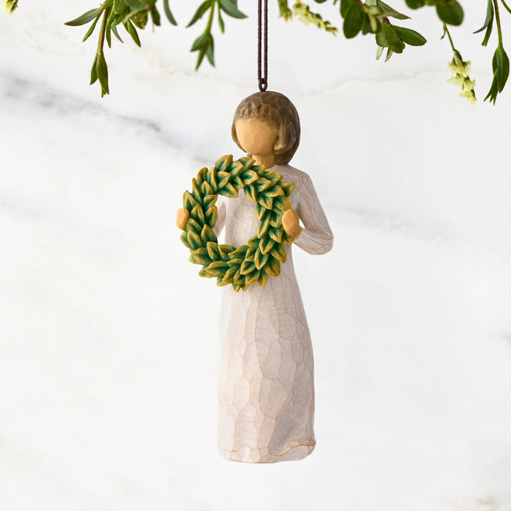 Figure in cream dress, holding green wreath of magnolia leaves in front of her. Hook and loop affixed to figure's head