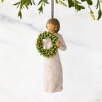 Figure in cream dress, holding green wreath of magnolia leaves in front of her. Hook and loop affixed to figure's head