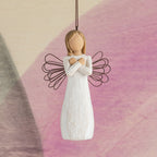 Willow Tree Sign for Love Ornament, 4.5”h hand-painted resin figure in cream dress with wire wings,  with crossed arms meaning "Love" in American Sign Language, brown elastic cord, hanging in front of pink painting