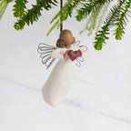 Front view: Darker-skin Angel with wire wings holding red heart. Hook and loop
