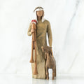 Wise man figurine standing in light brown attire with white headpiece, brown sheep at his feet