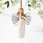 Female angel figure in cream dress with wire wings, holding brown dog in arms, ornament loop attached to head