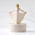 Front view: oval resin box, with 3-D figure in cream and gold carved dress atop lid