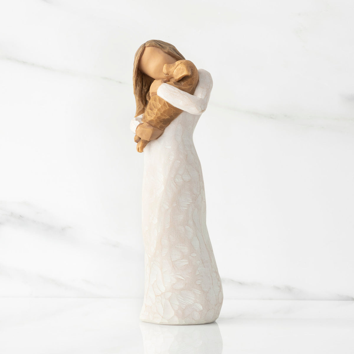 Left view, standing female figure in cream dress, holding golden color puppy in her arms