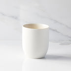 Back view of unglazed off-white tapered cylinder ceramic candle vessel