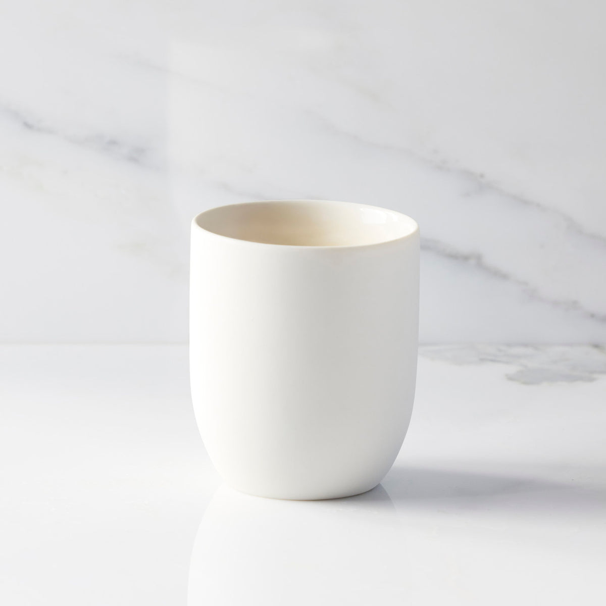 Back view of unglazed off-white tapered cylinder ceramic candle vessel