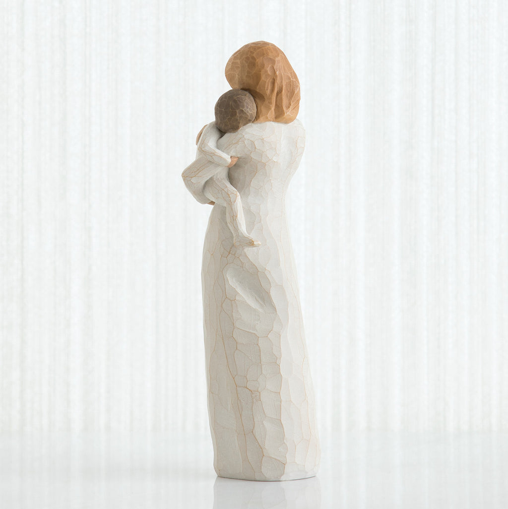 Back view of red haired woman figurine in white dress holding baby