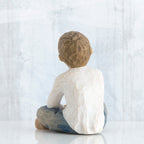 Back view of young brunette boy in white shirt and blue jeans sitting down