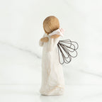 Side view of blonde angel figurine holding white seashell to her ear