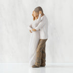 Left view of couple, standing with arms around each other. Woman has lighter skin and hair; man has darker skin and hair.