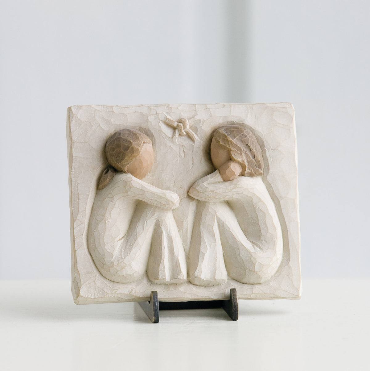 Small cream rectangle plaque with two girl figurines carved in sitting down facing one another