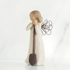 Young brunette girl figurine in white dress holding brown shovel