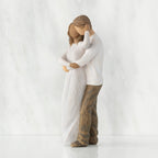 Left view of couple, standing with arms around each other. Woman has darker skin and hair; man has lighter skin and hair.