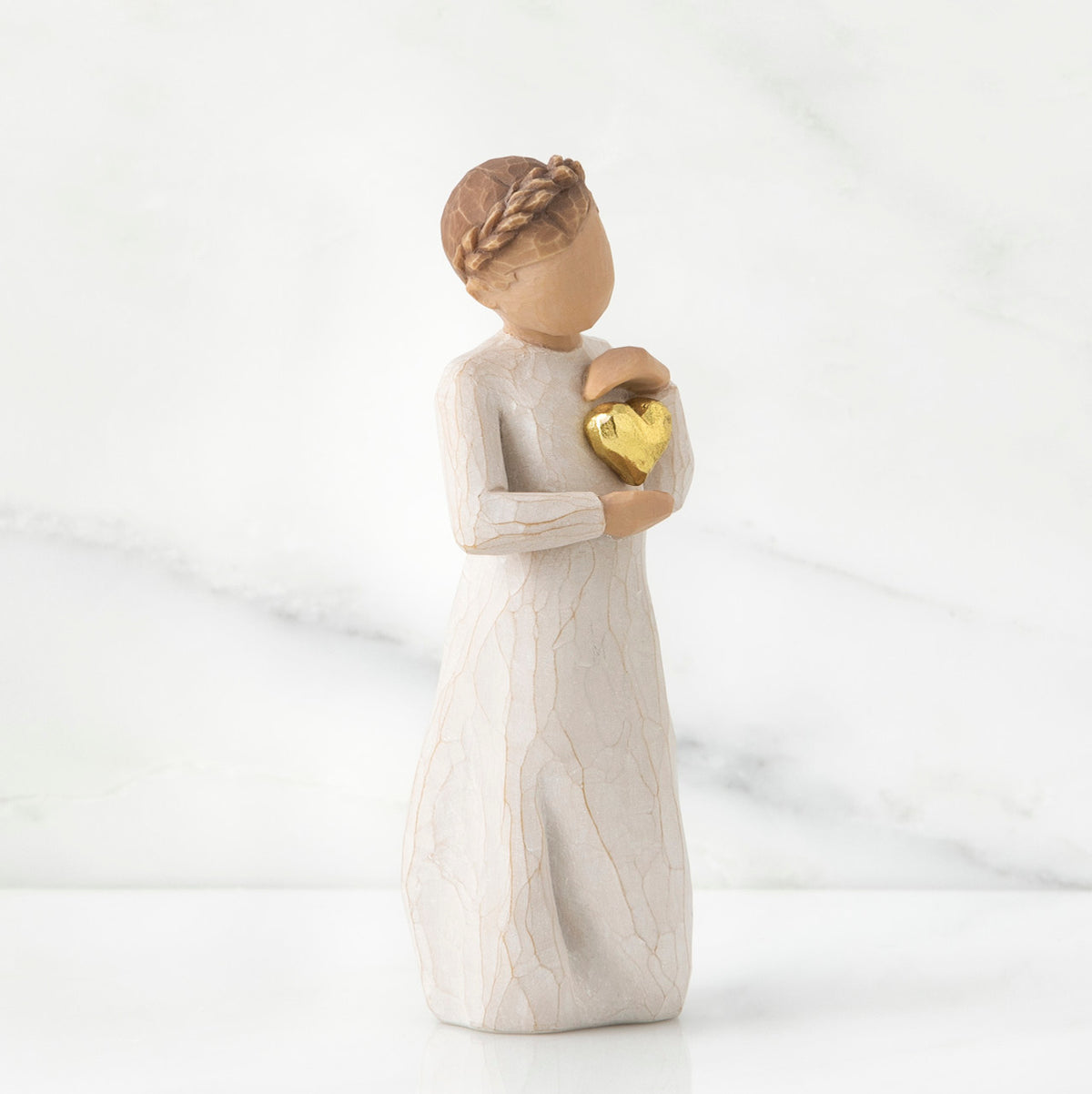 Brunette girl figurine in white dress holding gold heart