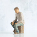 Left-facing view, adult male figure in light gray shirt and blue jeans, seated on gray rock