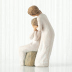 Left-facing view, seated older female in cream dress, with younger female in cream dress, standing at her shoulder, hands embracing