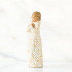 Gold haired woman in white/gold dress facing forward with arms to her chest