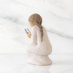 Left back view of kneeling female figure in cream dress, with wire butterfly on extended hands