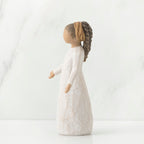 Side view of brunette girl figurine with braided ponytail wearing white dress standing up
