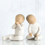 Set of two small baby figurines sitting in white facing each side