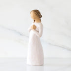 Left-facing view: Standing figure in cream dress with hands to heart in empathetic gesture