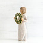 Right side view of young girl with bangs and short brown hair holding up a green, leafy wreath