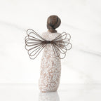 Back view: angel with wire wings, darker skin, dress carved with symbols of remembrance
