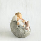 Small baby figurines laying on grey bean bag figurine