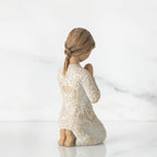 Back view of little brunette girl kneeling in white dress