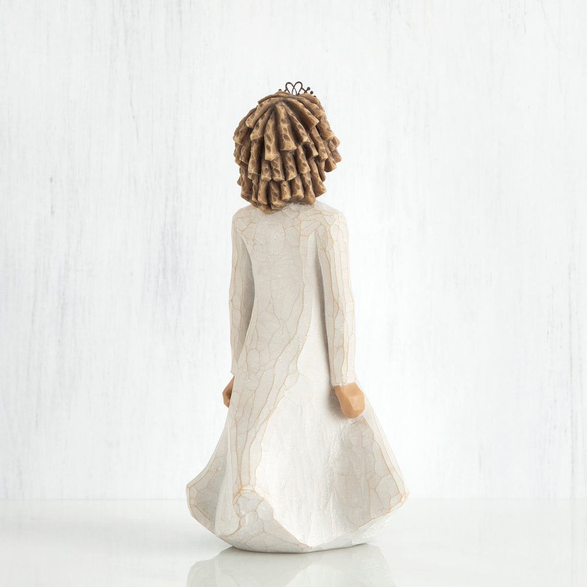 Back view of curly hair girl figurine in white dress standing up