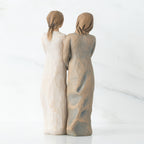 Back view of two woman figurines - one is in white, one is in brown