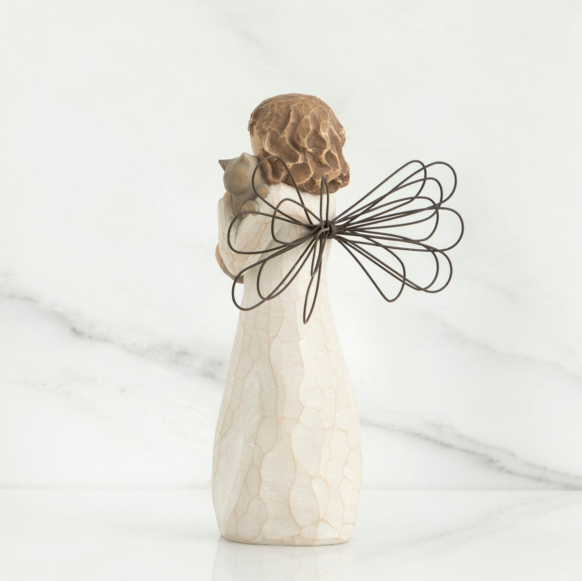Back view of brunette angel figurine in white dress holding grey cat
