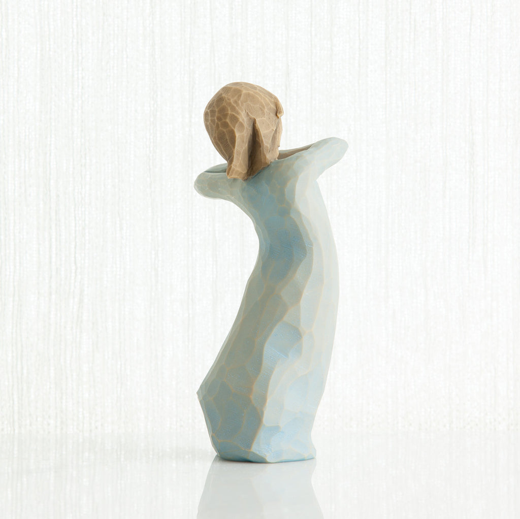 Back view of girl figurine in blue dress standing with her arms up