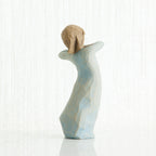 Back view of girl figurine in blue dress standing with her arms up