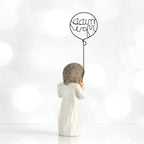 Back view of brunette small girl figurine in white dress holding up black wire balloon