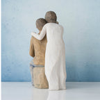 Woman figurine in white dress standing over man sitting down - all facing away from front