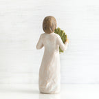 Back view of young girl with bangs and short brown hair holding up a green, leafy wreath
