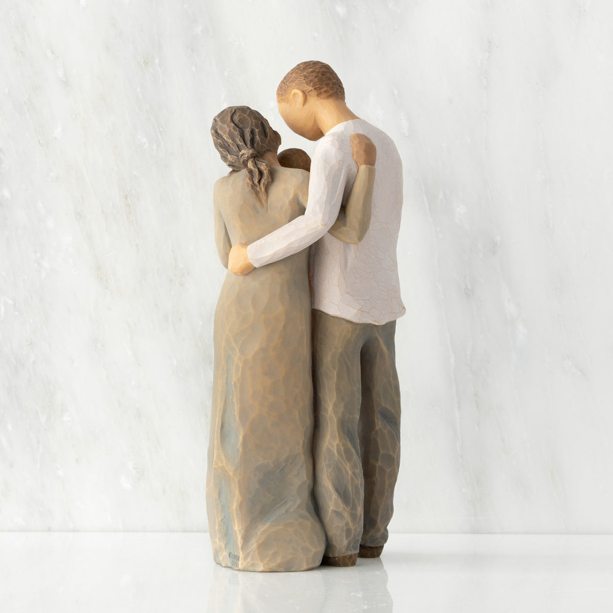Back view of standing couple, woman has darker skin and hair; man has lighter skin and hair, holding a baby between them.