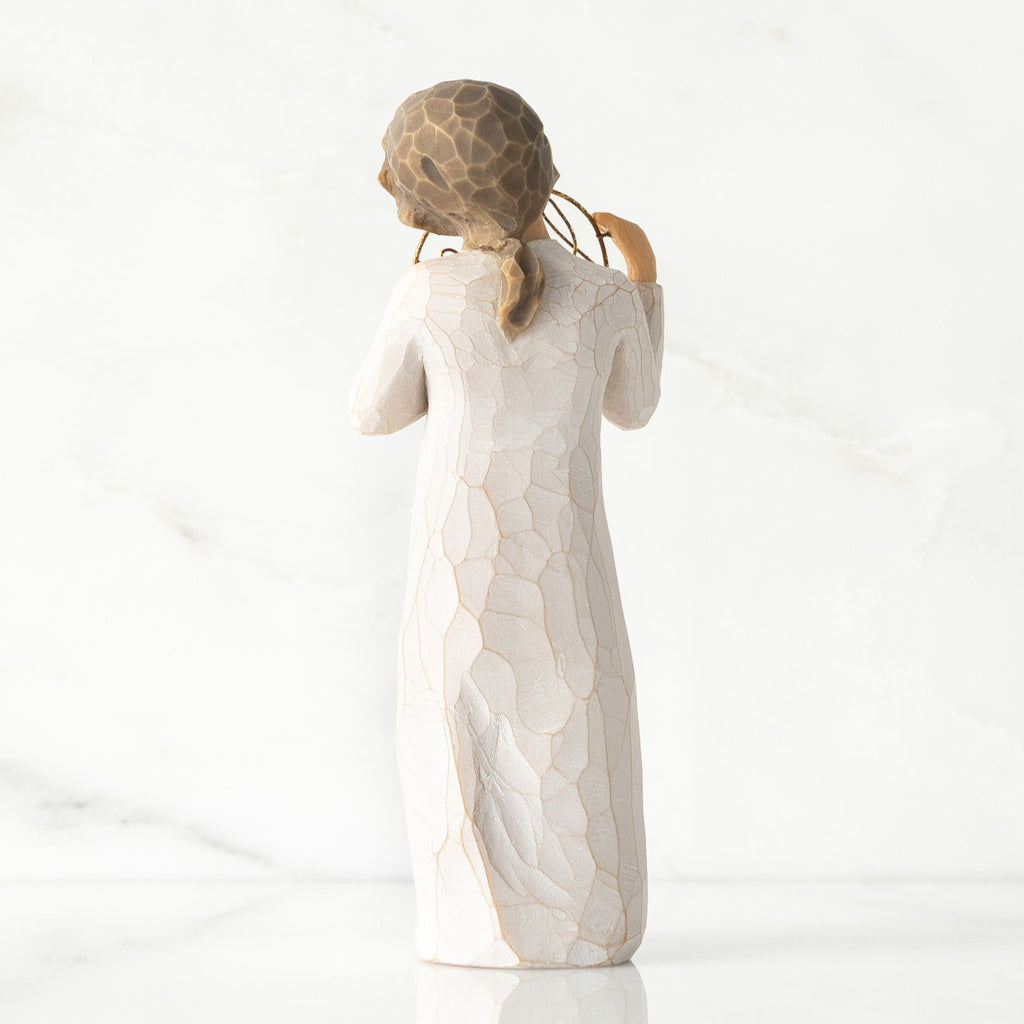 Back view, standing female figure in cream dress, holding gold wire circle in which is written 'love you'