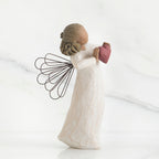 Side view of brunette angel girl figurine in white dress holding pink heart figurine