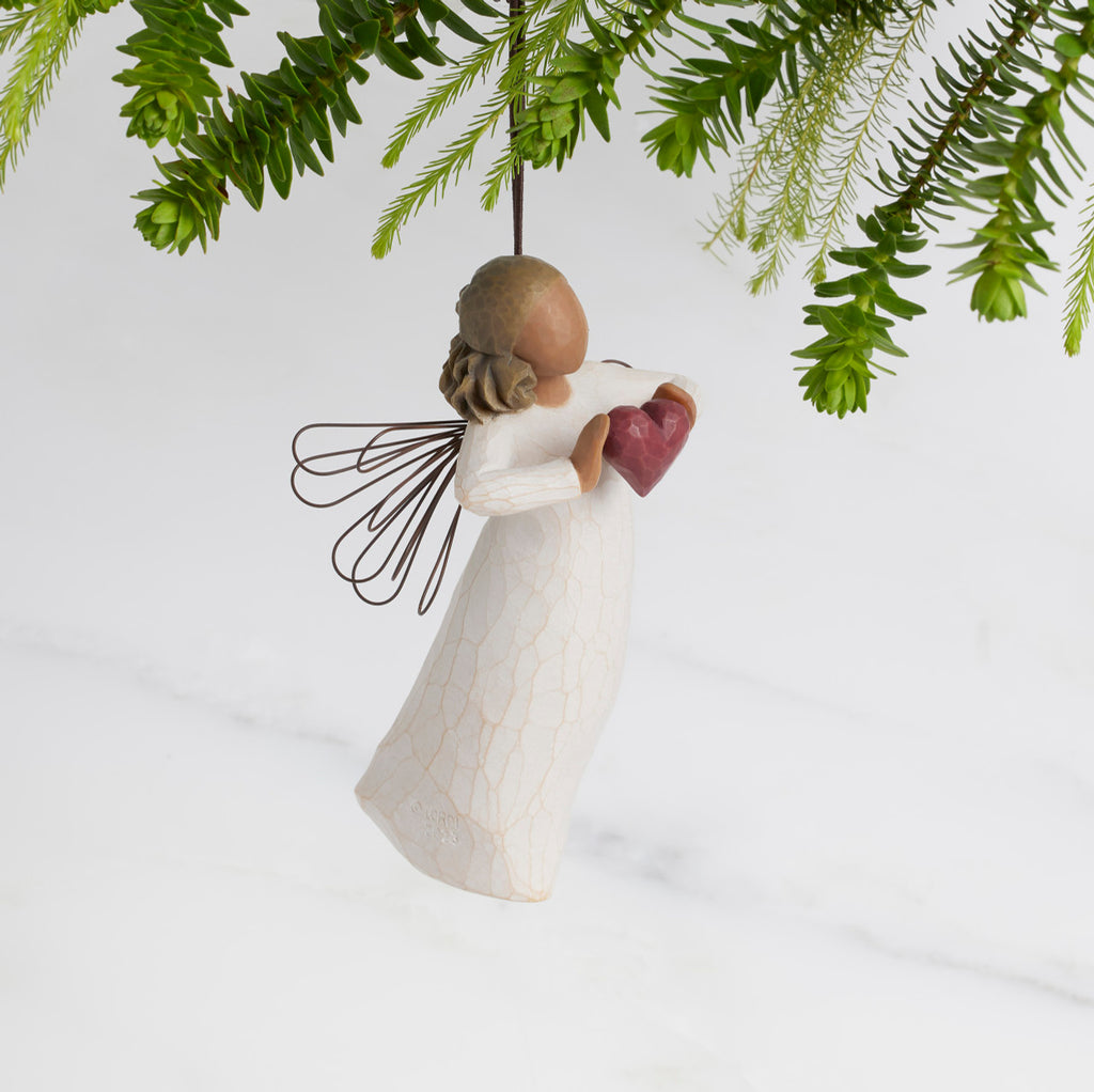 Facing right: Darker-skin Angel with wire wings holding red heart. Loop and hook attached in wings