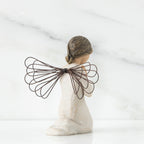 Small girl figurine in white with brown wings kneeling with hands folded