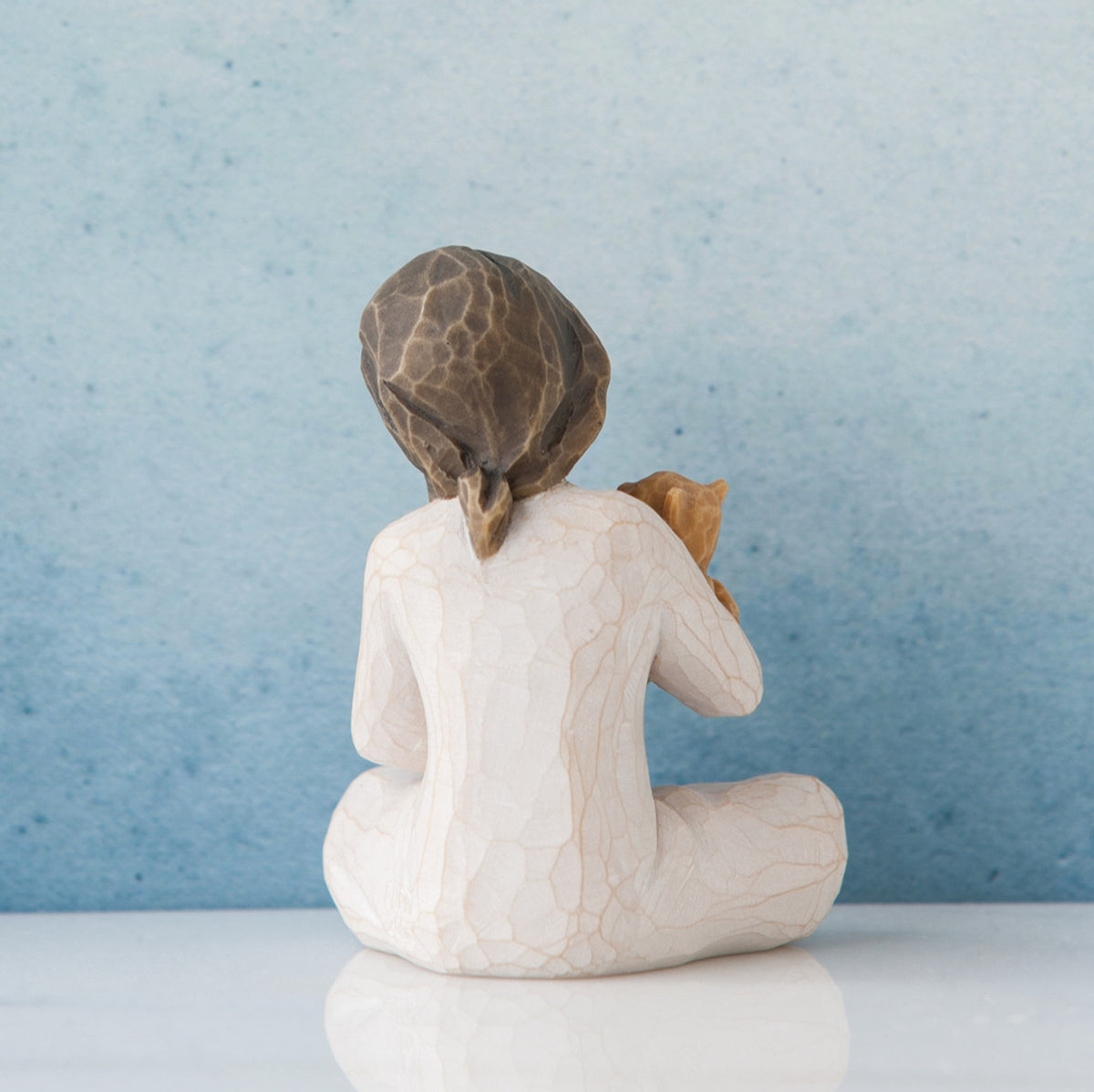 Small brunette girl in white facing away from the front towards the blue wall