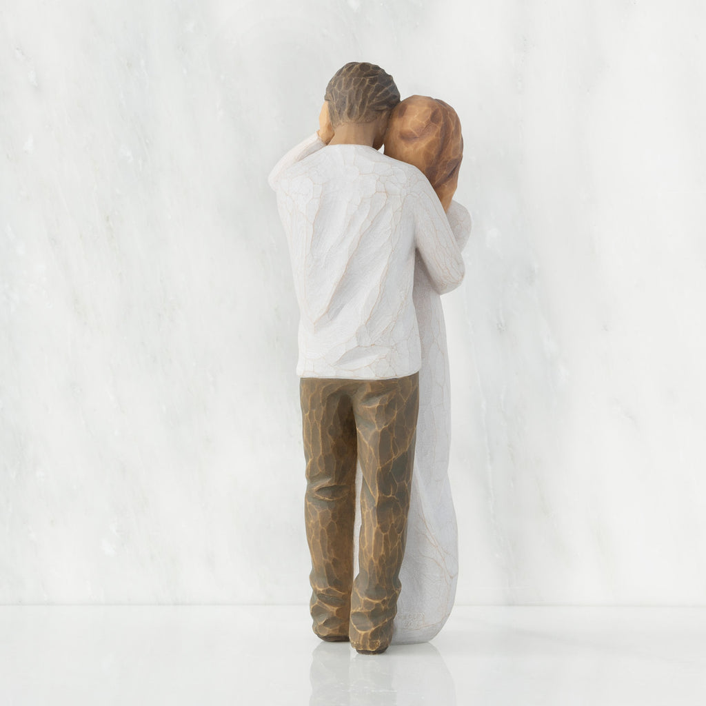 Back view of couple, standing with arms around each other. Woman has lighter skin and hair; man has darker skin and hair.